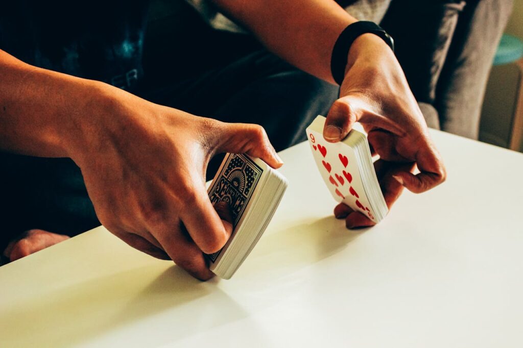 The Art of Drawing Readers In: Your attractive post title goes here A person skillfully shuffles a deck of poker playing cards on a table indoors.