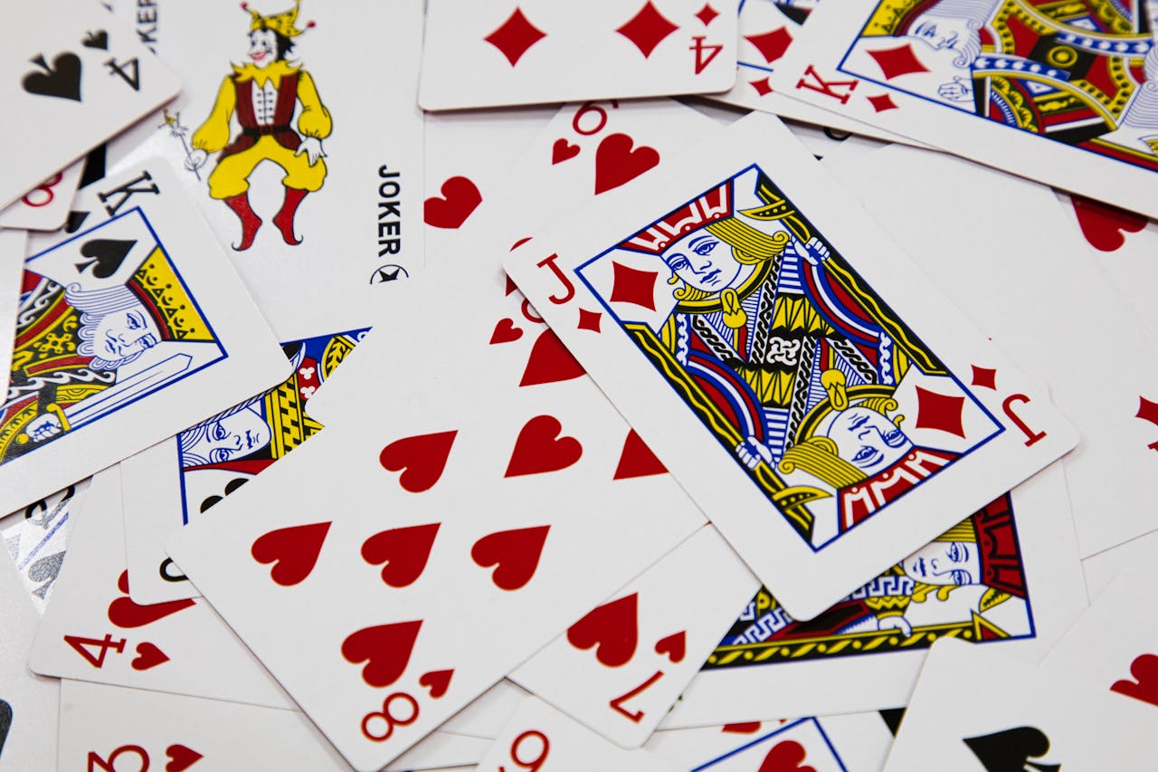 A vibrant arrangement of playing cards depicting various suits and a joker in a dynamic composition.
